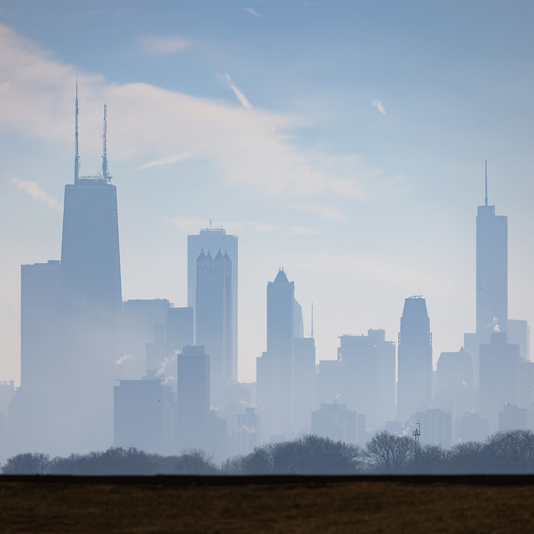 Chicago skyline on a misty day with iconic skyscrapers against a pale blue sky.